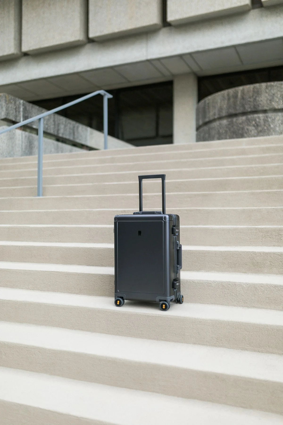 Black rolling suitcase standing on concrete steps