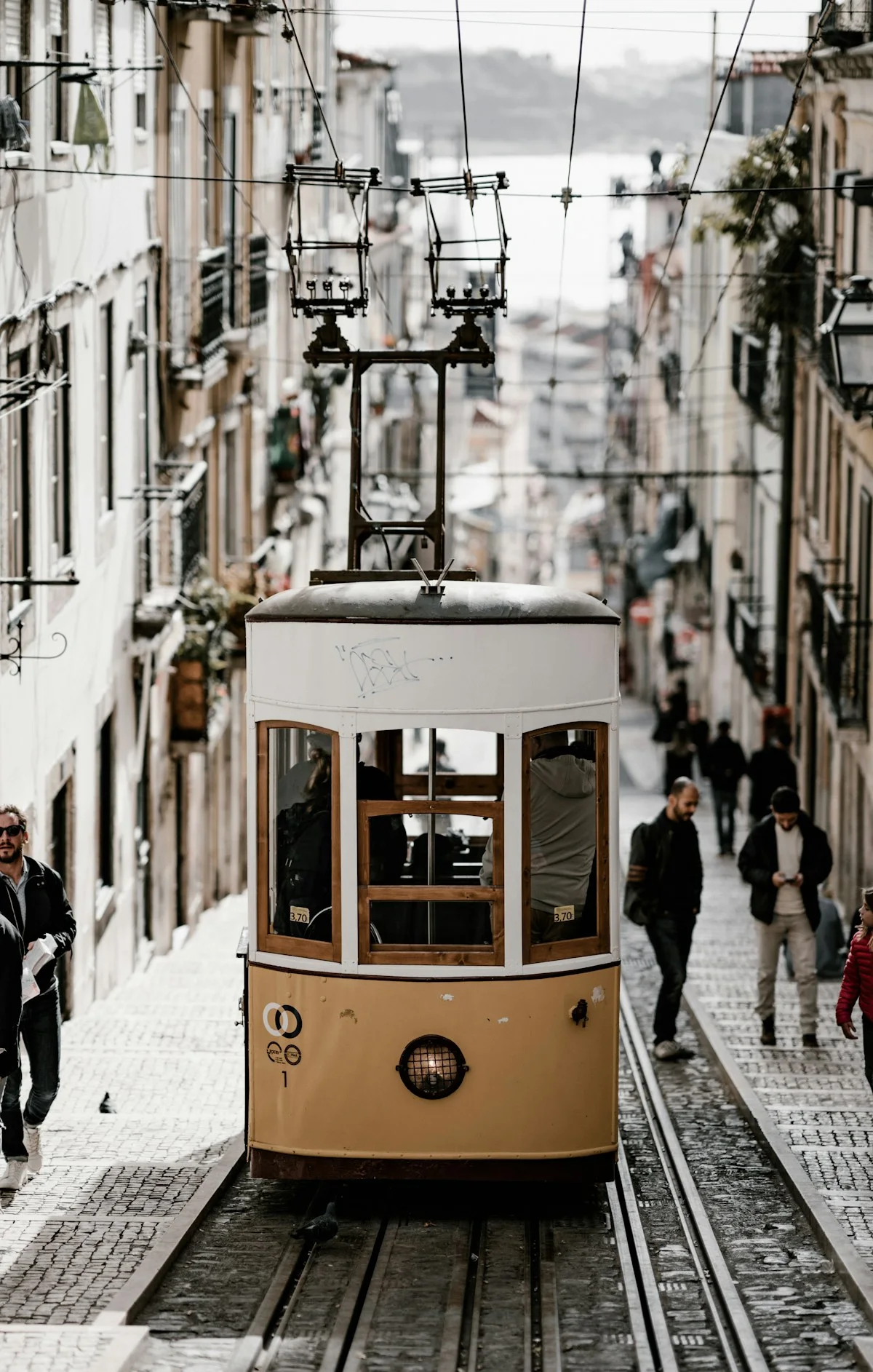 Tram on a narrow street lined with buildings in Lisbon