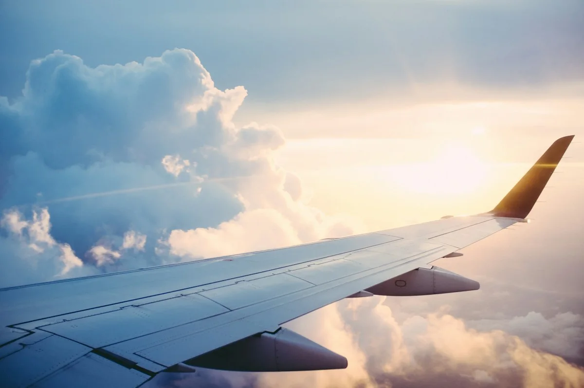Airplane wing above clouds in warm sunlight