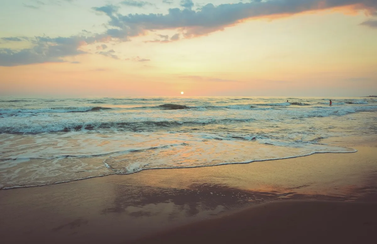 Gentle waves reaching a sandy beach at sunset