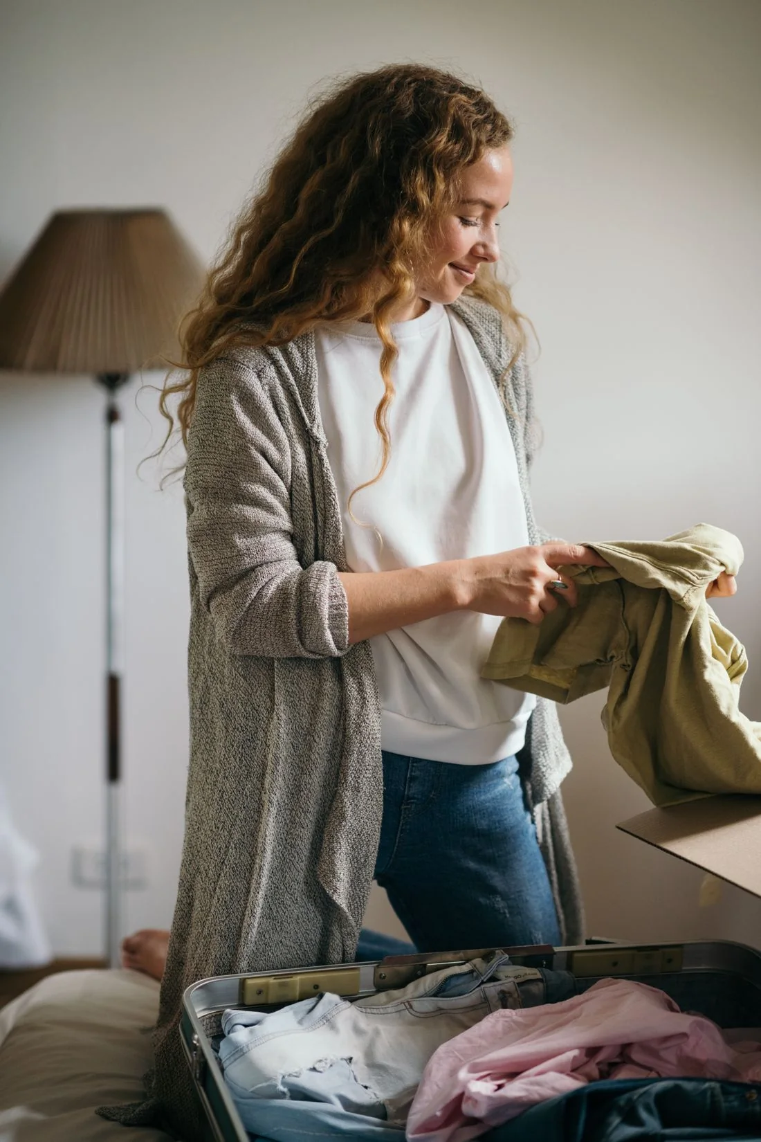 Woman packing clothes into a suitcase in a bedroom