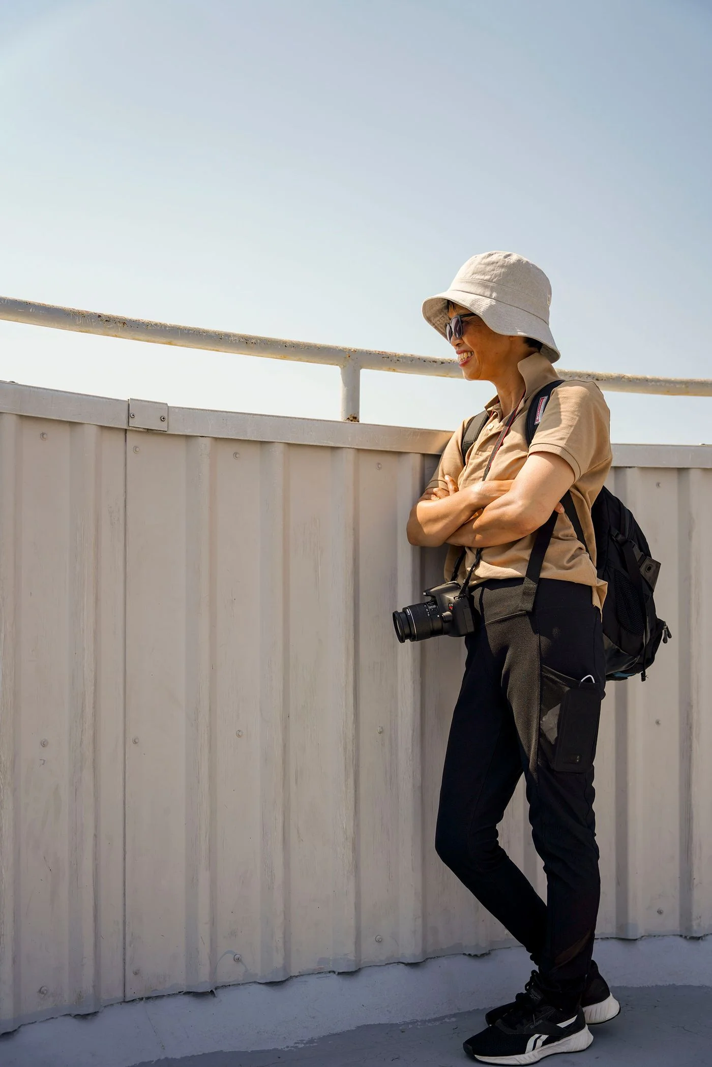 A traveler carrying a camera and backpack while standing outdoors.