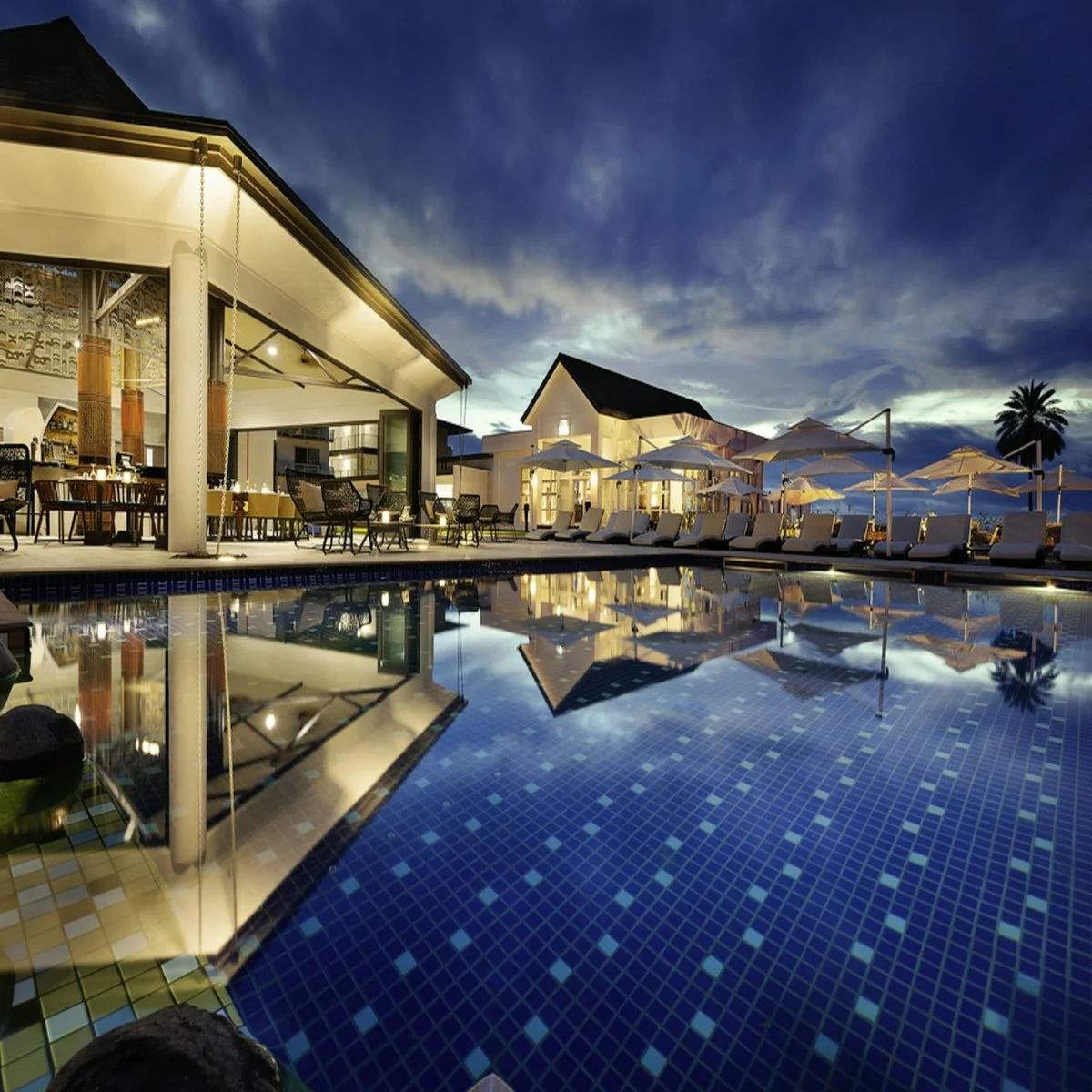 Resort swimming pool and buildings lit at dusk
