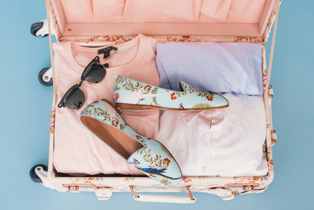 Open pink suitcase with clothes, accessories and internal retaining straps
