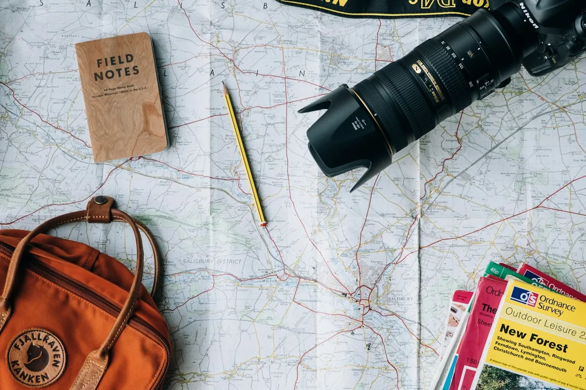 A map, travel bag and camera laid out for planning a trip