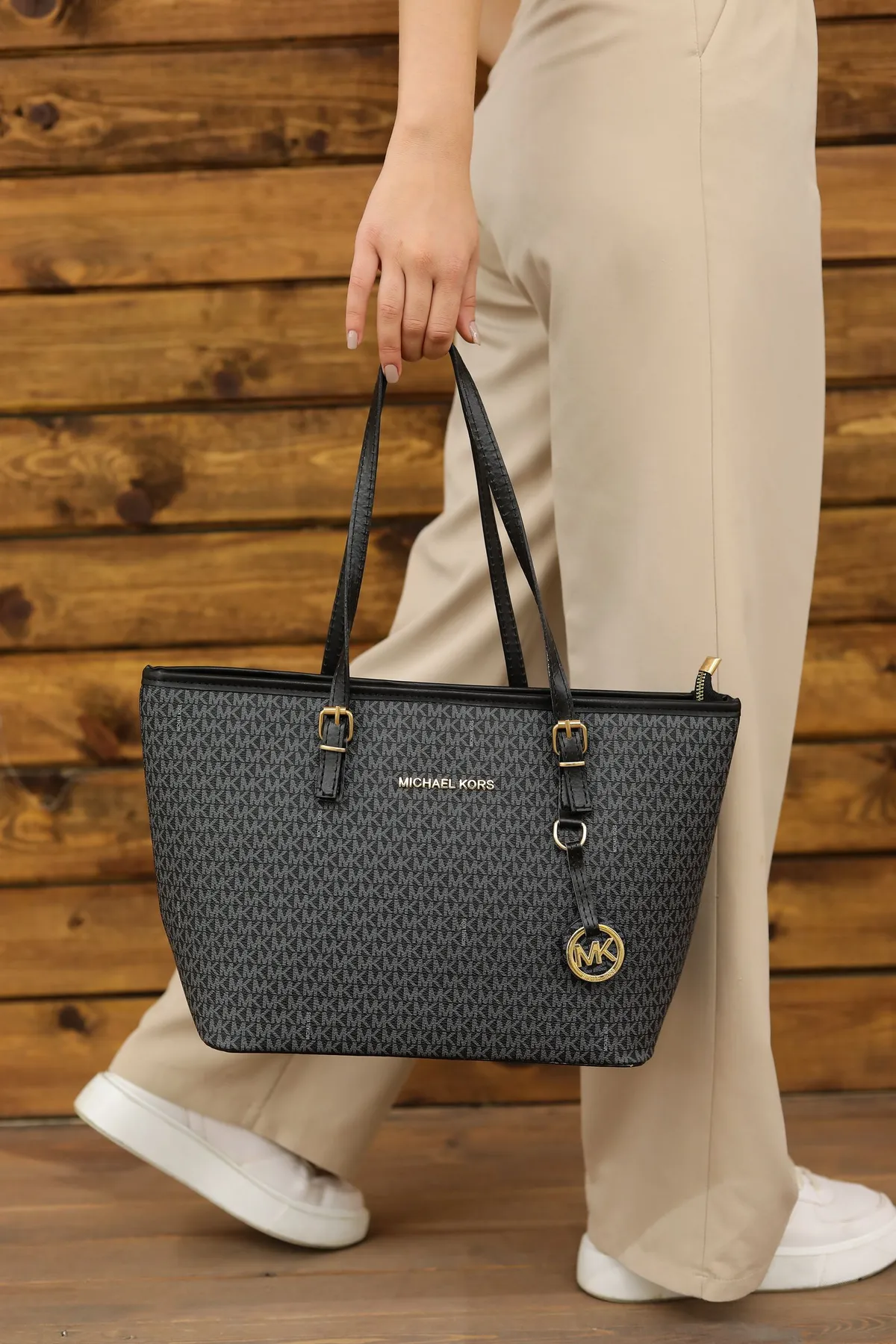 Person holding a dark patterned tote bag with black handles and gold-coloured details