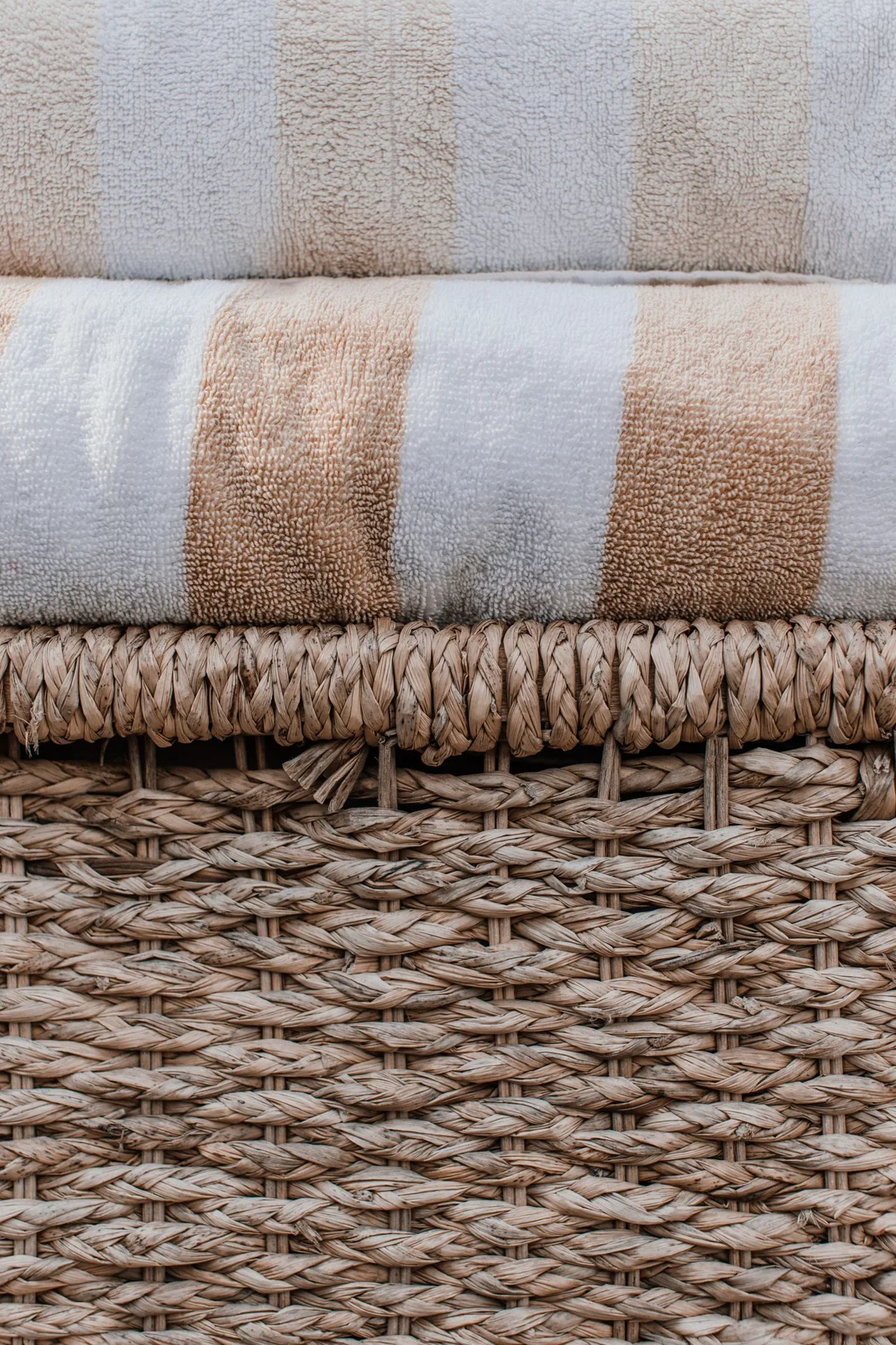 Folded striped towels resting on a woven basket