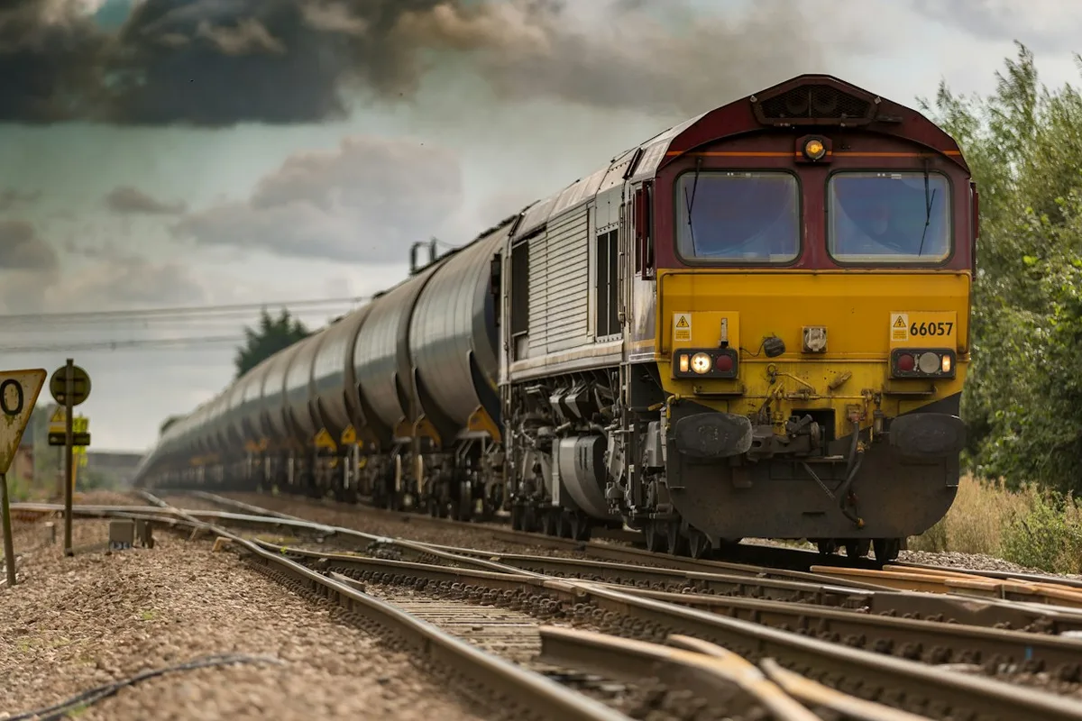A freight train with a yellow front travelling on railway tracks