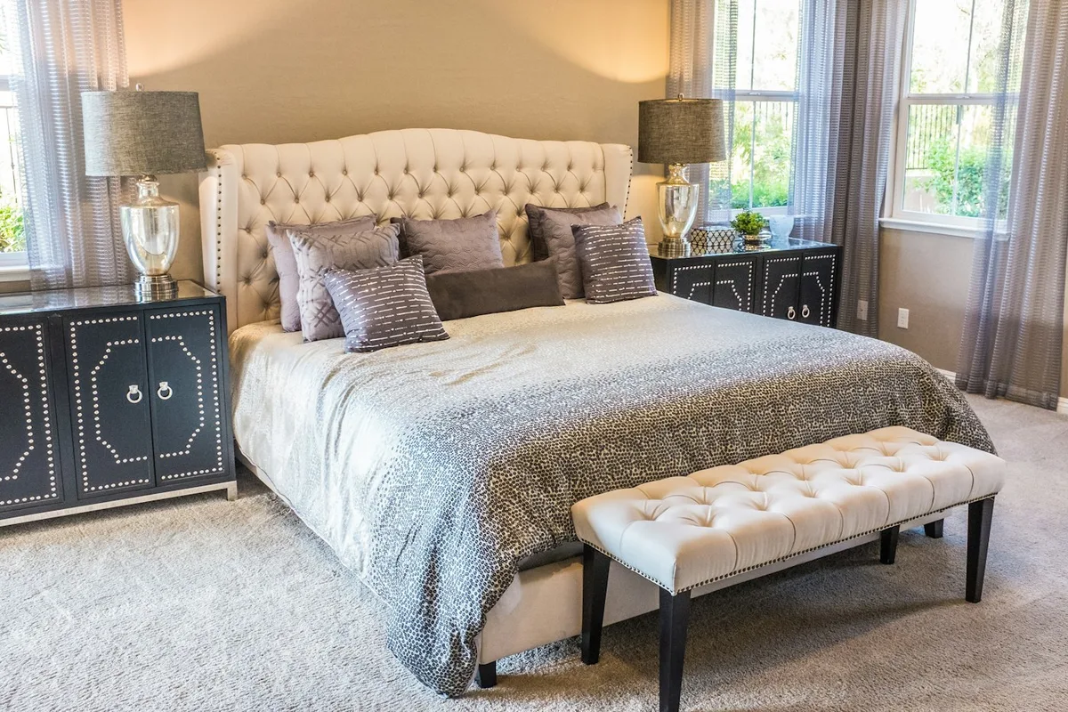 A bed dressed in layered neutral linen in a bright bedroom