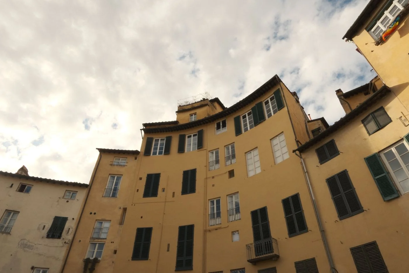 Historic yellow buildings around a square in Lucca.