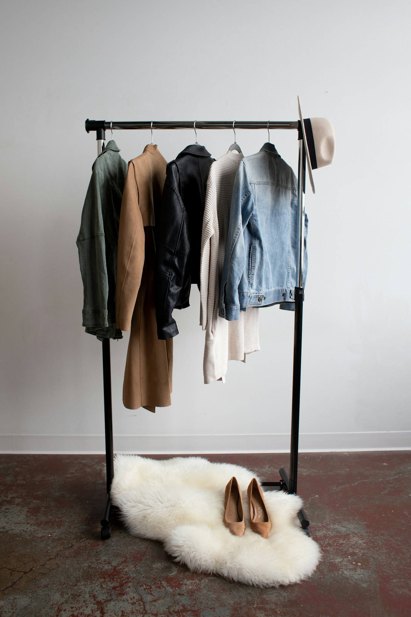 Coats and everyday garments arranged on a rail above shoes